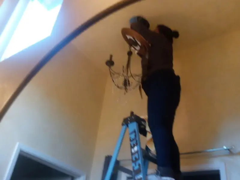 Electrician installing a chandelier in a Bennett residence